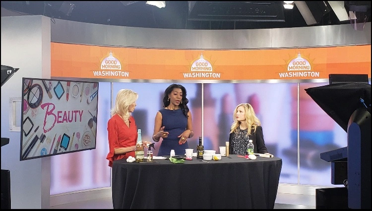 Three women discussing beauty products on TV set.