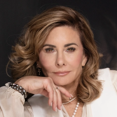 Woman with wavy hair and pearl jewelry.